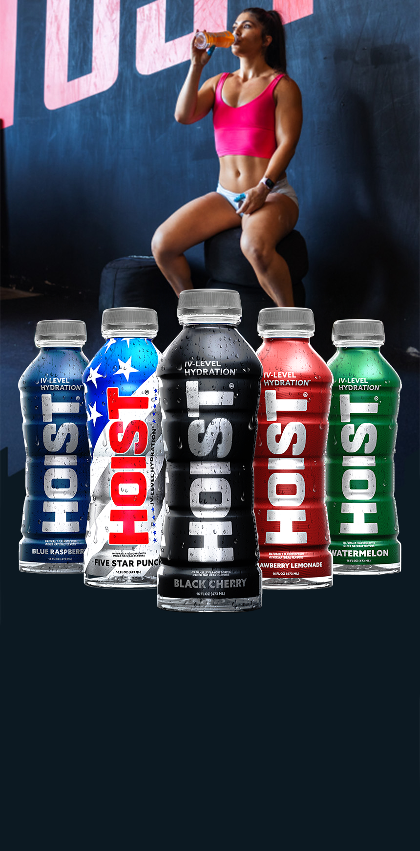 Person in sports attire holding a drink with six bottles of Hoist drinks in front